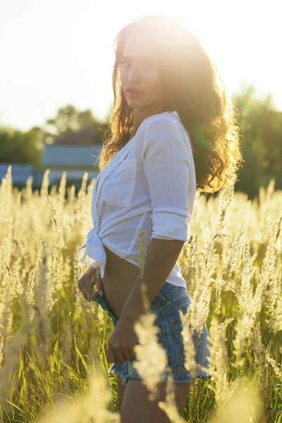 Young beautiful brunette woman in a white shirt and blue denim s — Stock Photo, Image