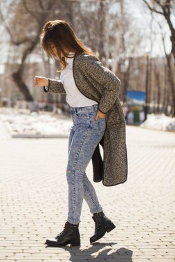 Gri bir ceket ve mavi kot esmer kız bahar parkında yürür
