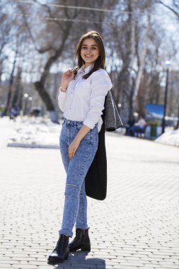 Genç kız içinde beyaz gömlek ve mavi kot Walks içinde Spring Park