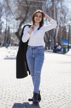 Genç kız içinde beyaz gömlek ve mavi kot Walks içinde Spring Park