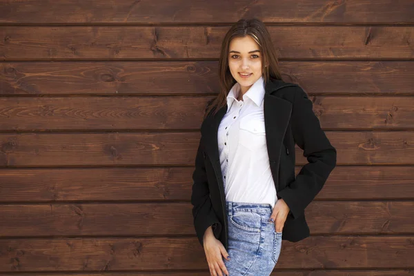 Happy teenager girl in a white shirt on a wooden wall background — Stock Photo, Image