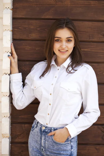 木製の壁の背景に白いシャツで幸せなティーンエイジャーの女の子 — ストック写真