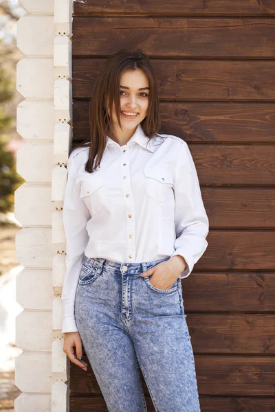 Gelukkig tiener meisje in een wit overhemd op een houten muur achtergrond — Stockfoto