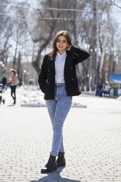 Teenie-Mädchen in weißem Hemd und blauer Jeans spaziert im Frühlingspark — Stockfoto