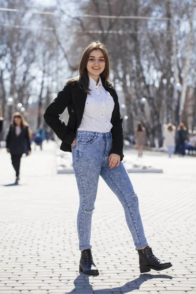 穿着白衬衫和蓝色牛仔裤的少女在春天公园散步 — 图库照片