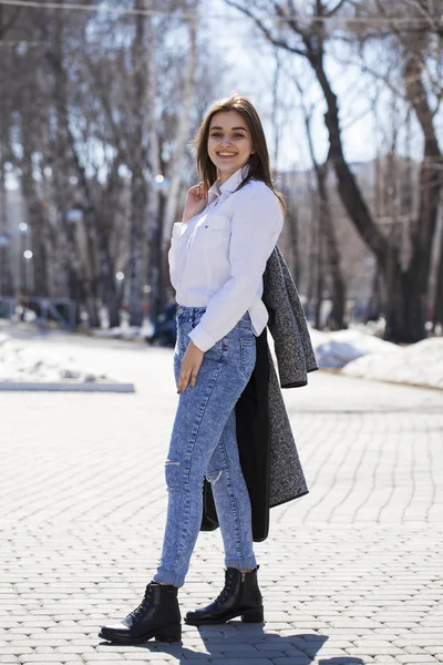 Teenie-Mädchen in weißem Hemd und blauer Jeans spaziert im Frühlingspark — Stockfoto