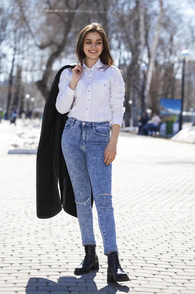 Teenie-Mädchen in weißem Hemd und blauer Jeans spaziert im Frühlingspark — Stockfoto