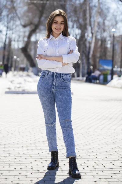 Teenie-Mädchen in weißem Hemd und blauer Jeans spaziert im Frühlingspark — Stockfoto