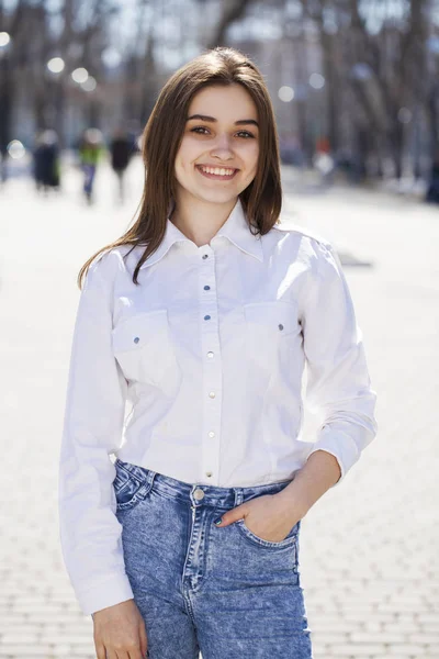 Junge schöne brünette Mädchen in weißem Hemd posiert auf Frühling pa — Stockfoto