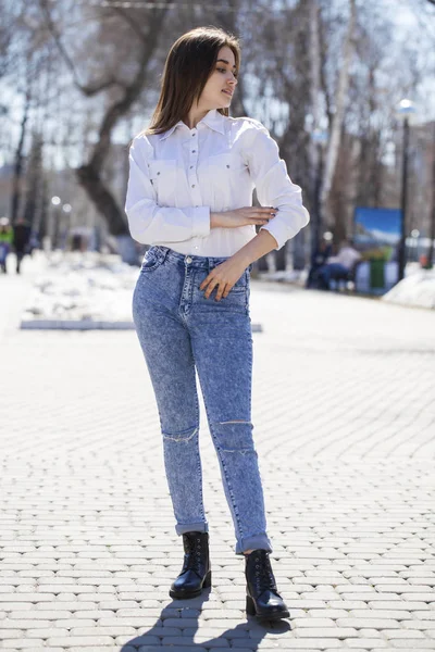 Teenie-Mädchen in weißem Hemd und blauer Jeans spaziert im Frühlingspark — Stockfoto