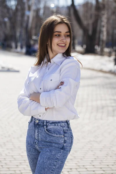 Junge schöne brünette Mädchen in weißem Hemd posiert auf Frühling pa — Stockfoto