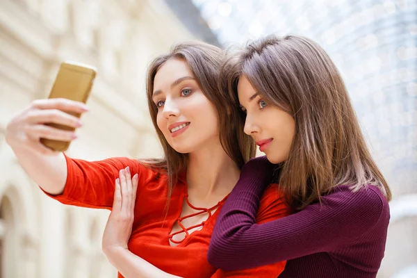 Dos mujeres sonrientes se toman una foto con un teléfono inteligente —  Fotos de Stock