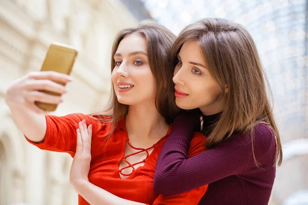 Dos mujeres sonrientes se toman una foto con un teléfono inteligente — Foto de Stock