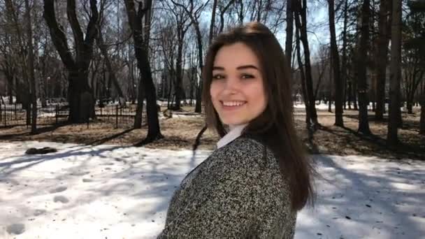 Jeune belle fille brune en manteau gris posant sur le parc de printemps — Video