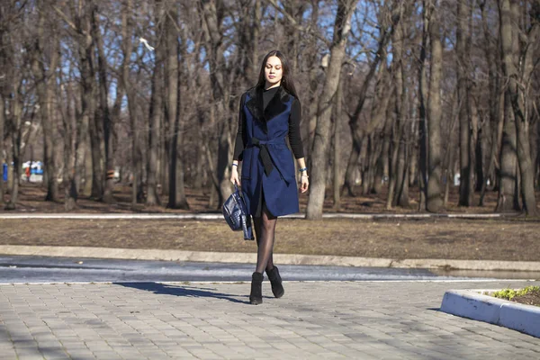 Portrait of a young beautiful woman in blue coat with a bag walk — Stock Photo, Image