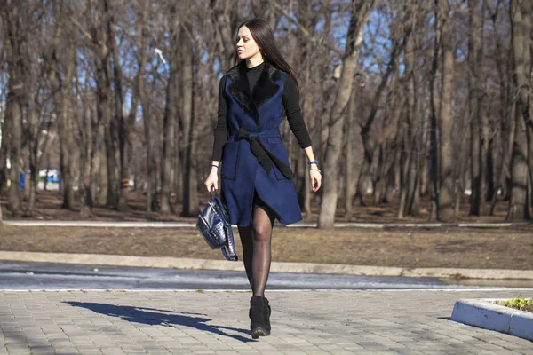 Portrait of a young beautiful woman in blue coat with a bag walk — Stock Photo, Image