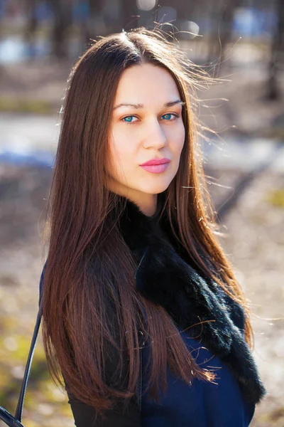 Портрет молодой красивой женщины в синем пальто в весеннем парке — стоковое фото