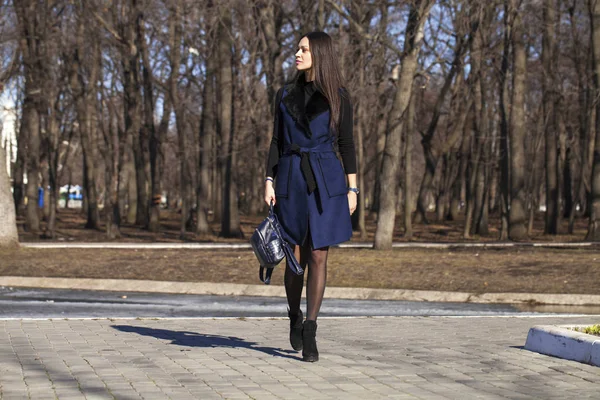Portrait of a young beautiful woman in blue coat with a bag walk — Stock Photo, Image