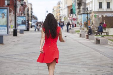 Yaz caddesinde yürüyen kırmızı elbiseli güzel bir kadın.