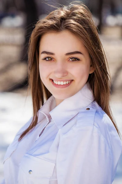 Young beautiful brunette girl in white shirt posing on spring pa — Stock Photo, Image