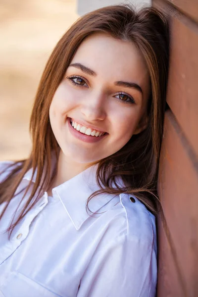 Chica adolescente feliz en una camisa blanca sobre un fondo de pared de madera — Foto de Stock