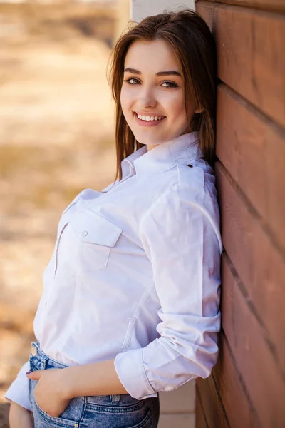 Chica adolescente feliz en una camisa blanca sobre un fondo de pared de madera — Foto de Stock