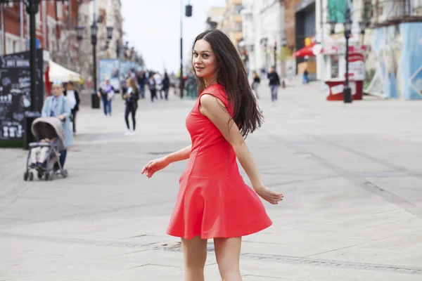 Mladá krásná žena v červených šatech chůze v letní ulici — Stock fotografie