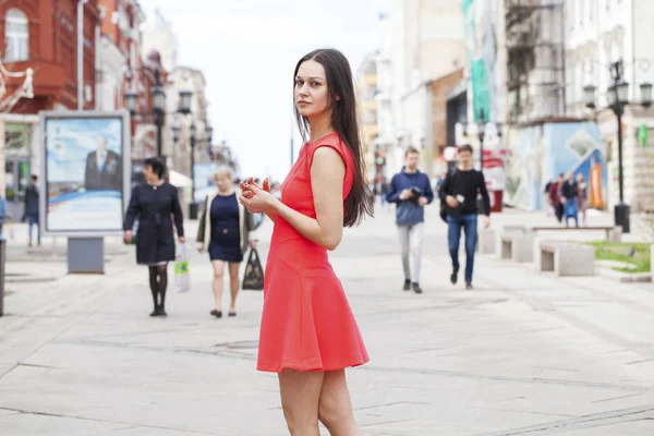 빨간 드레스를 입은 아름다운 여성 이 여름 거리를 걷고 있습니다. — 스톡 사진