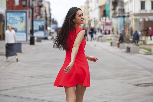 Jonge mooie vrouw in rode jurk wandelen in de zomer straat — Stockfoto