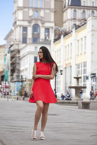 Jeune belle femme en robe rouge marchant dans la rue d'été — Photo