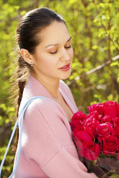 赤いバラの花束を持つ若い美しい女性の肖像 — ストック写真