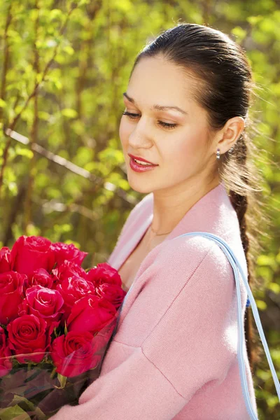 一个年轻美丽的女人与一束红玫瑰的肖像 — 图库照片