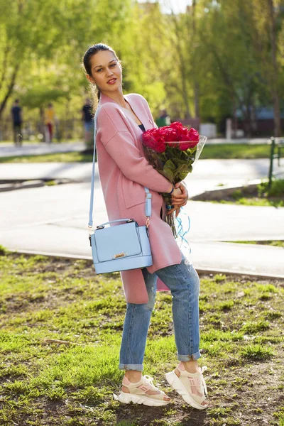 Portrait d'une jeune belle femme avec un bouquet de roses rouges — Photo