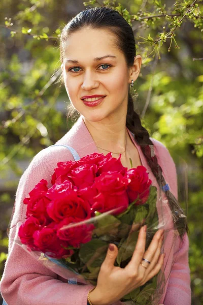 Portret van een jonge mooie vrouw met een boeket rode rozen — Stockfoto