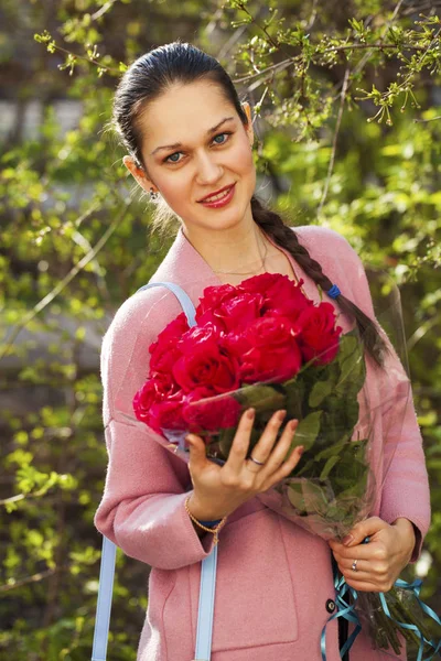 Portret van een jonge mooie vrouw met een boeket rode rozen — Stockfoto