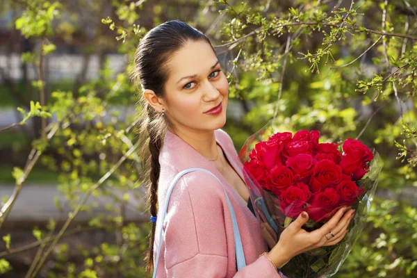 Portret van een jonge mooie vrouw met een boeket rode rozen — Stockfoto