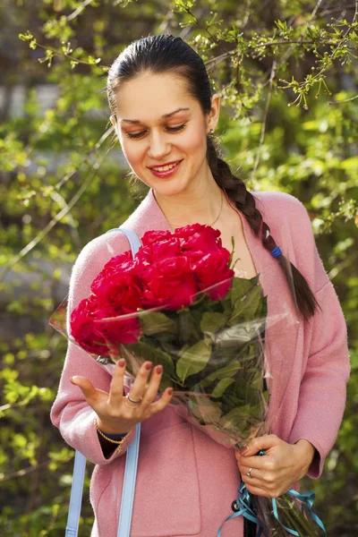 Portret van een jonge mooie vrouw met een boeket rode rozen — Stockfoto