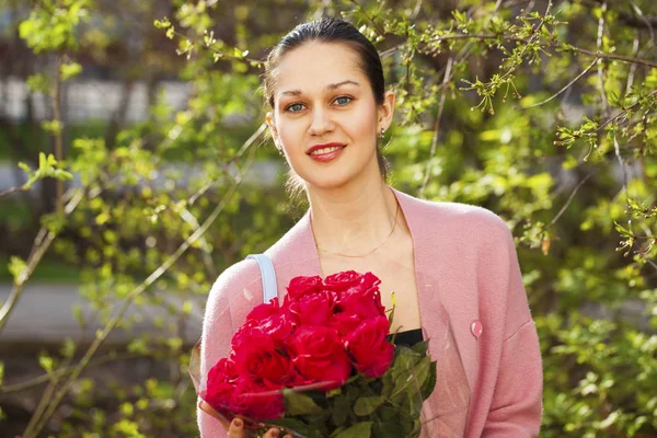 Portrait of a young beautiful woman with a bouquet of red roses — Stock Photo, Image