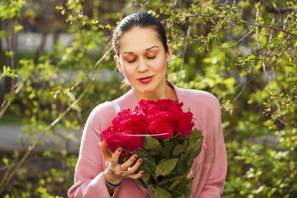 Portrét mladé krásné ženy s kyticí rudými růžemi — Stock fotografie