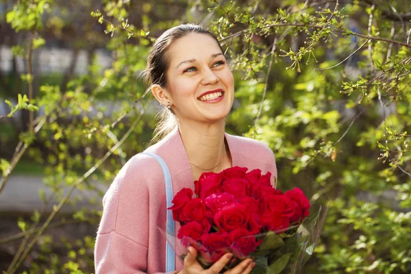 Portret van een jonge mooie vrouw met een boeket rode rozen — Stockfoto