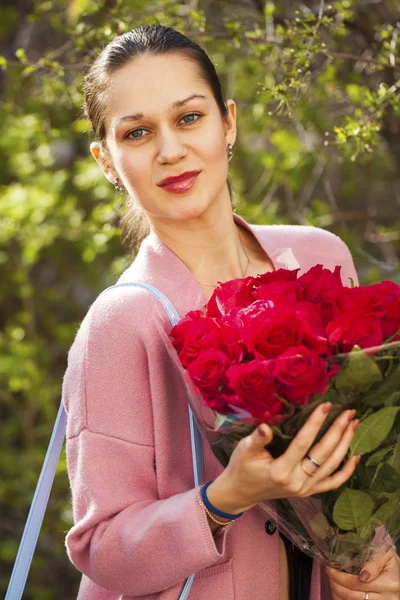 Portret van een jonge mooie vrouw met een boeket rode rozen — Stockfoto