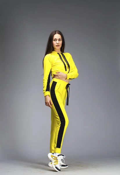 Portrait of a young beautiful brunette woman in yellow tracksuit — Stock Photo, Image