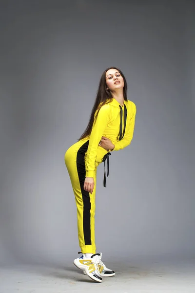 Portrait of a young beautiful brunette woman in yellow tracksuit — Stock Photo, Image