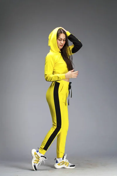 Porträt einer jungen schönen brünetten Frau im gelben Trainingsanzug — Stockfoto