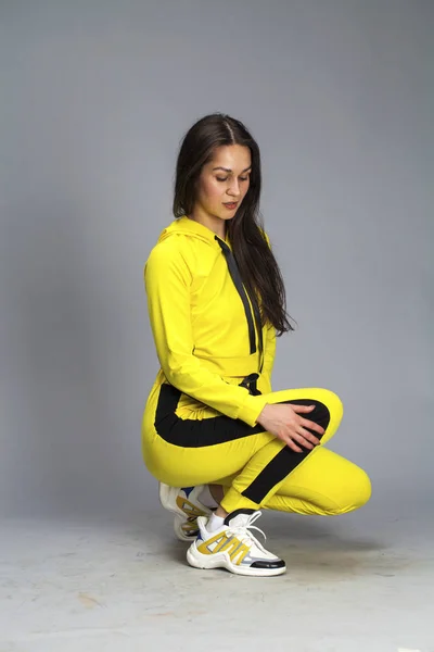 Портрет молодой красивой брюнетки в жёлтом спортивном костюме — стоковое фото