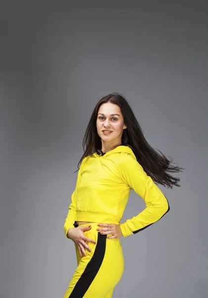 黄色のトラックスーツを着た若い美しいブルネット女性の肖像 — ストック写真