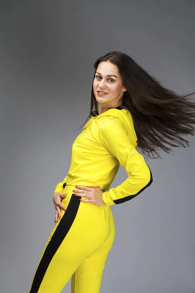 Portret van een jonge mooie brunette vrouw in gele trainingspak — Stockfoto