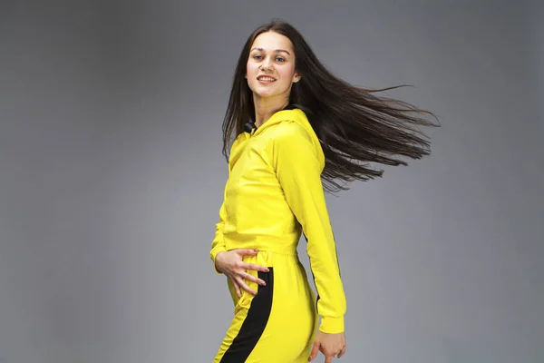 一个年轻的美丽的黑发女人在黄色运动服的肖像 — 图库照片