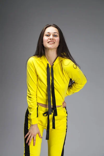 Portrait of a young beautiful brunette woman in yellow tracksuit — Stock Photo, Image