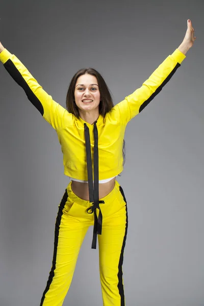 Portret van een jonge mooie brunette vrouw in gele trainingspak — Stockfoto